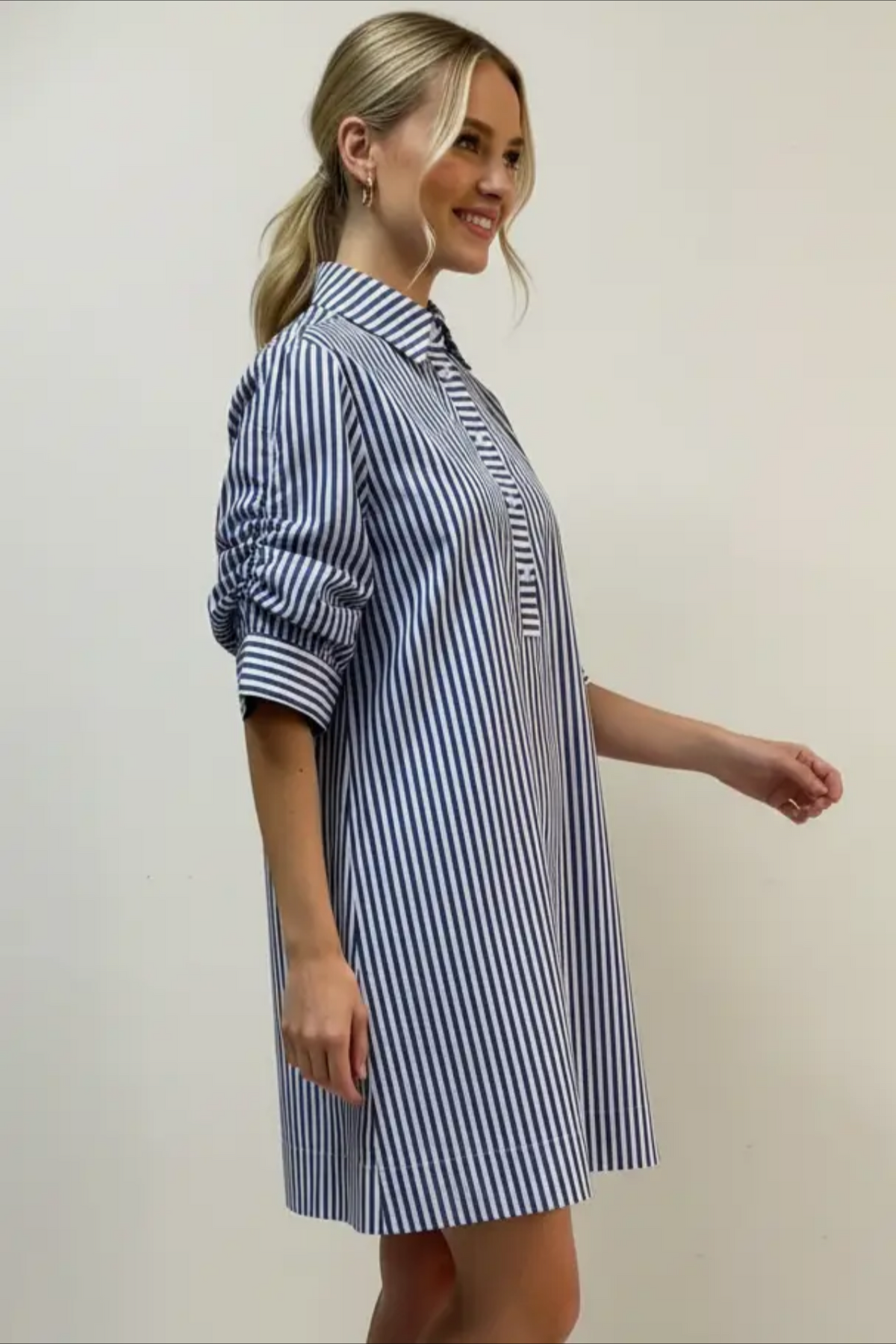 Woman wearing a blue and white striped dress against a plain background