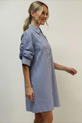Woman wearing a blue and white striped dress against a plain background
