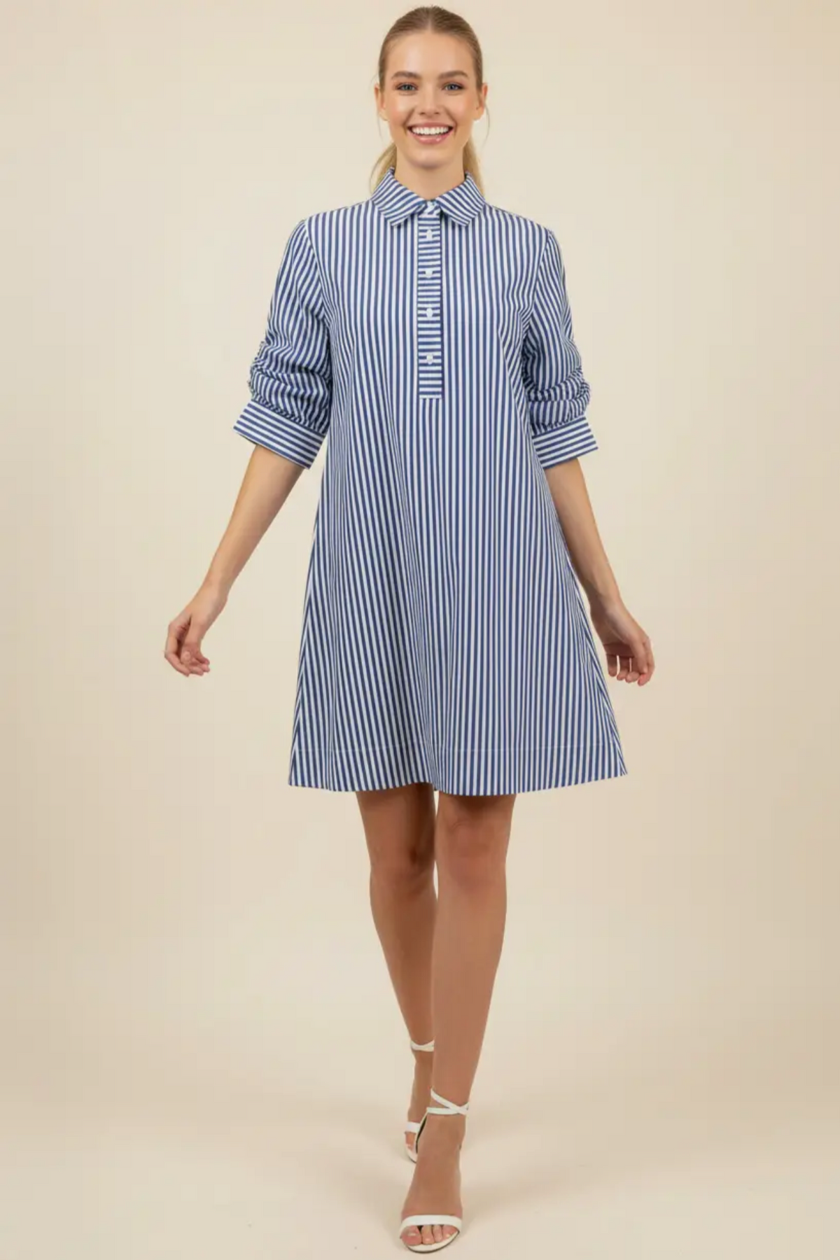 Woman wearing a blue and white striped dress on a beige background