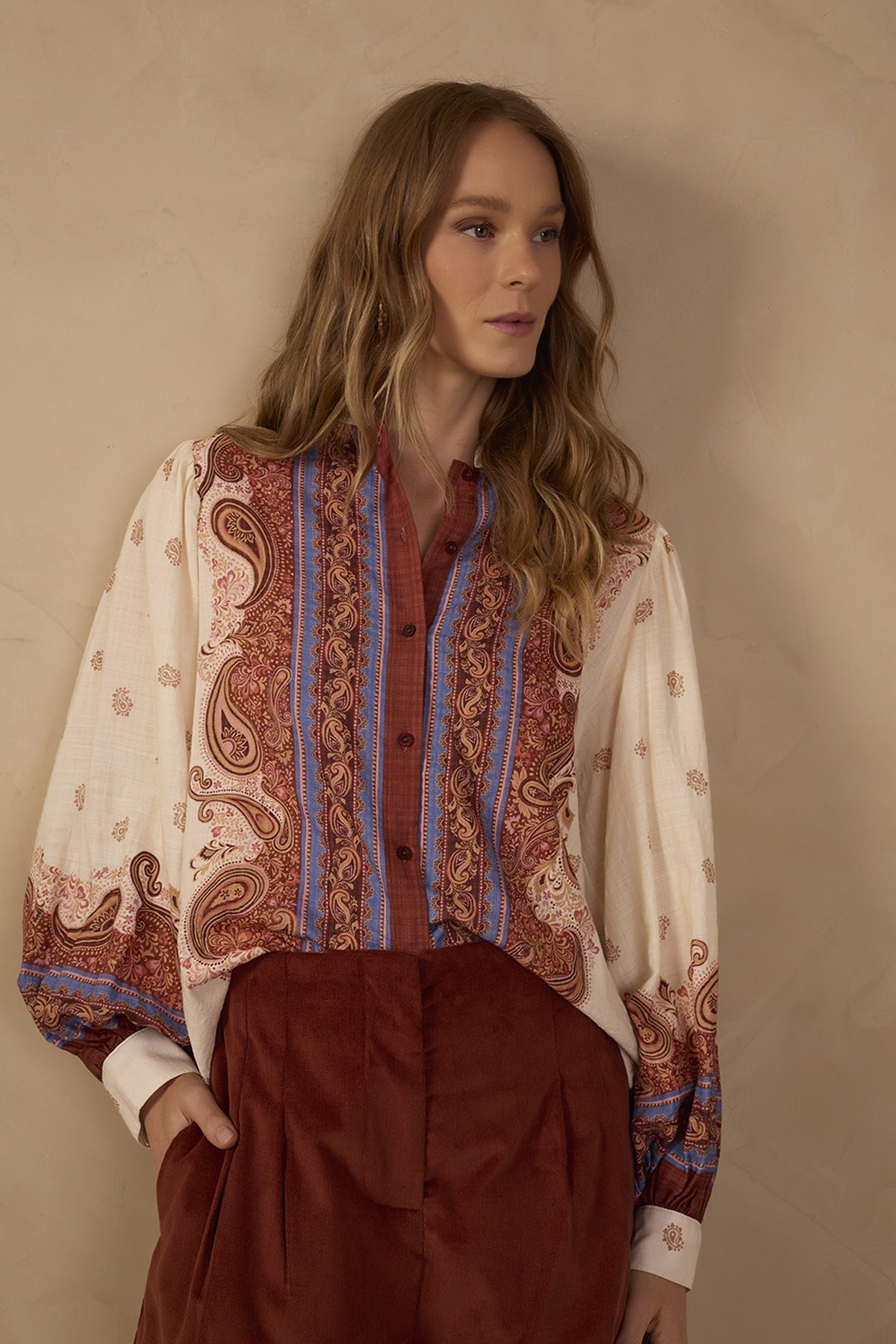 Model wearing the Off-White Poema Collared Buttoned Shirt featuring rust brown and blue ornamental print details, long sleeves, a classic collar, and front buttons, styled with brown tailored trousers.