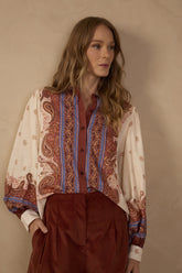 Model wearing the Off-White Poema Collared Buttoned Shirt featuring rust brown and blue ornamental print details, long sleeves, a classic collar, and front buttons, styled with brown tailored trousers.